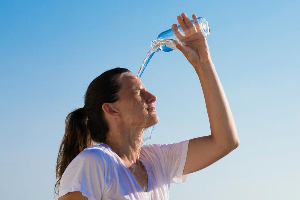 muito calor: mulher jogando água na cabeça